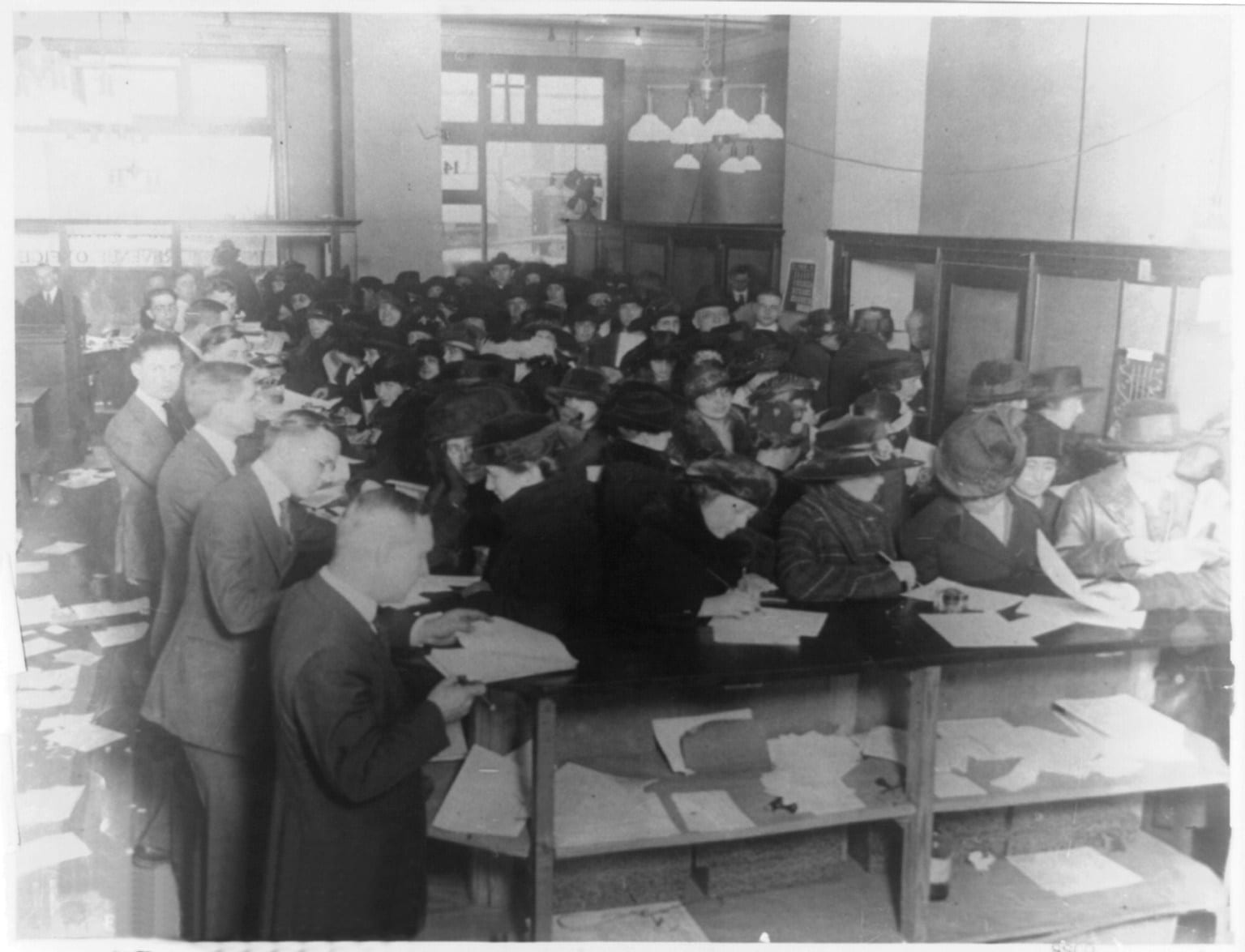 Circa-1920 press photo captioned Everybody's doing it, doing what, paying taxes of course, showing stacks of tax forms