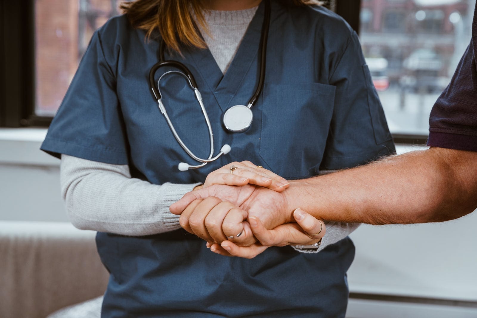A clinician holding a patient's hand in a gesture of comfort