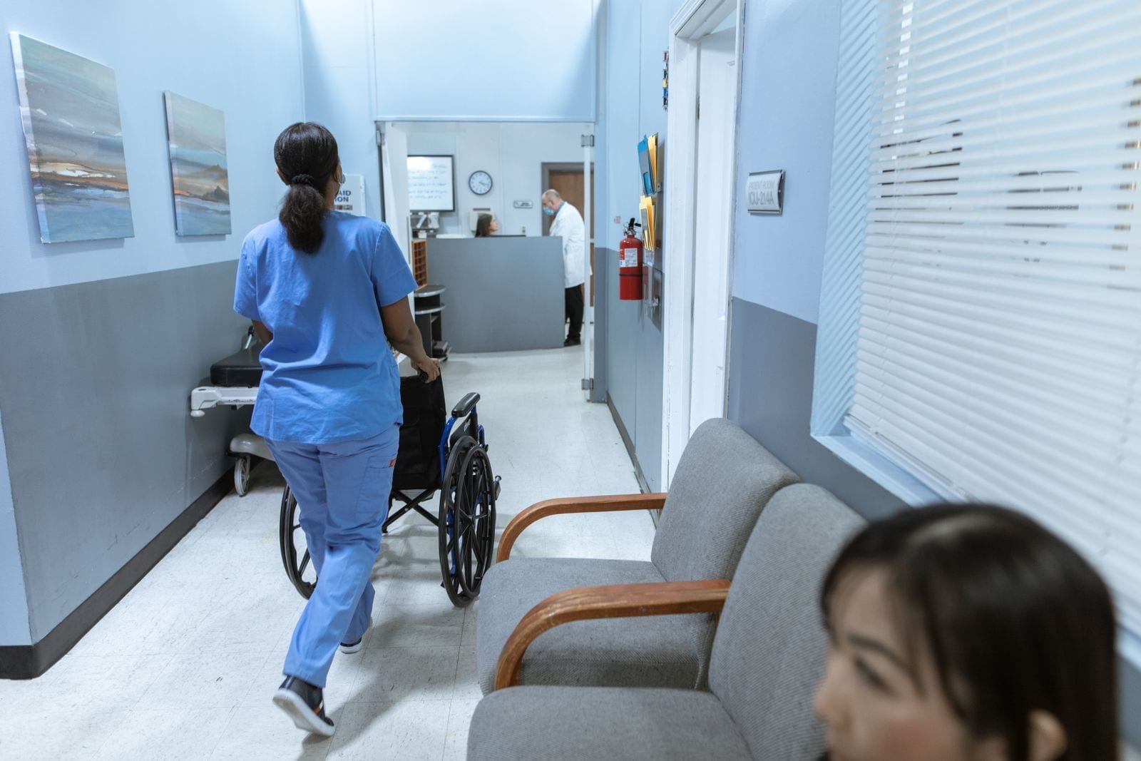 A nurse pushing a wheelchair through a hospital hallway