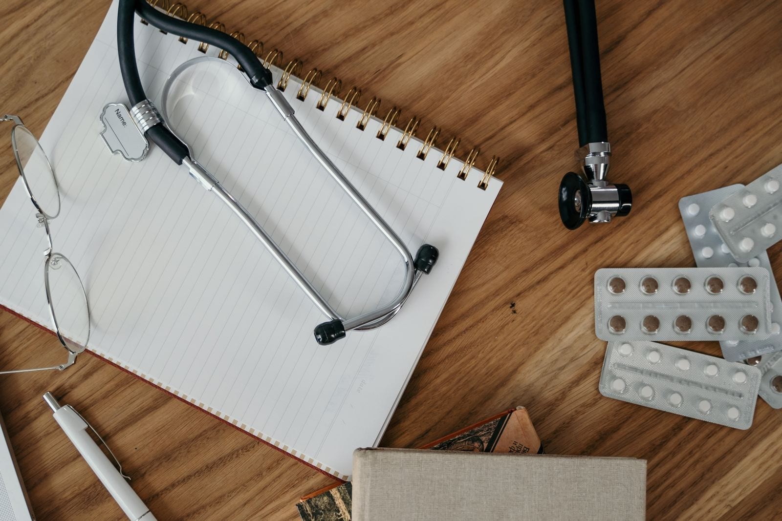 A stethoscope and notebook on a wooden desk