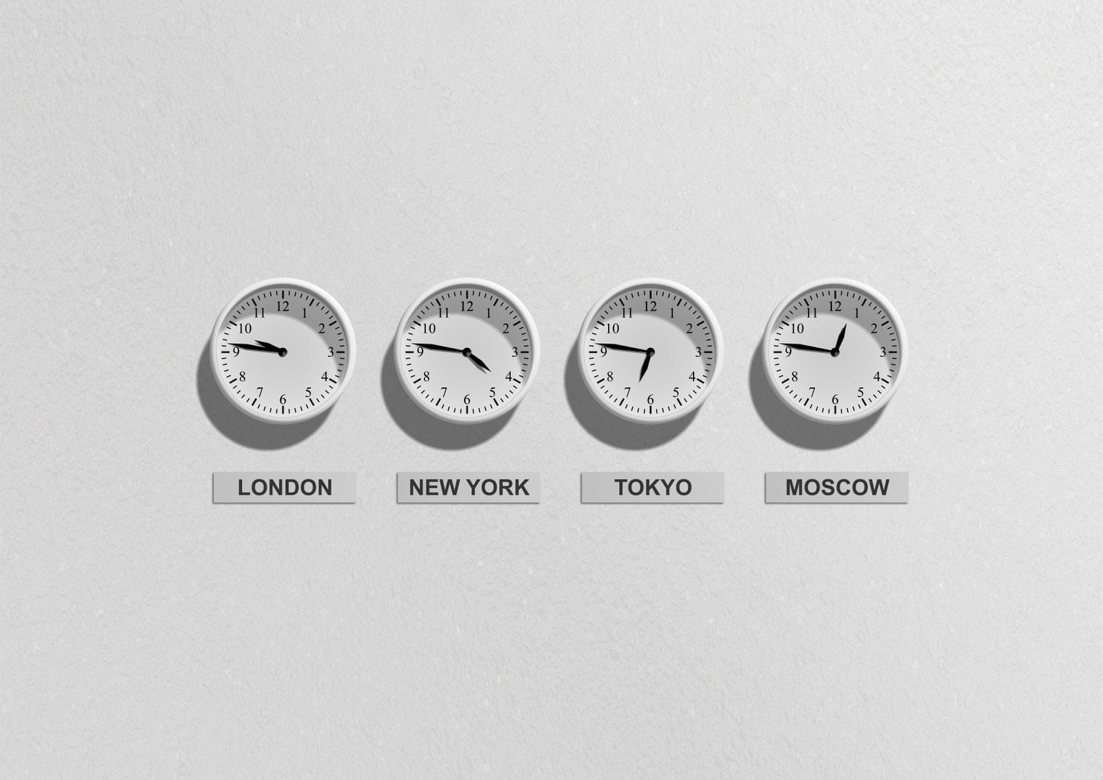 Four wall clocks showing different time zones side by side