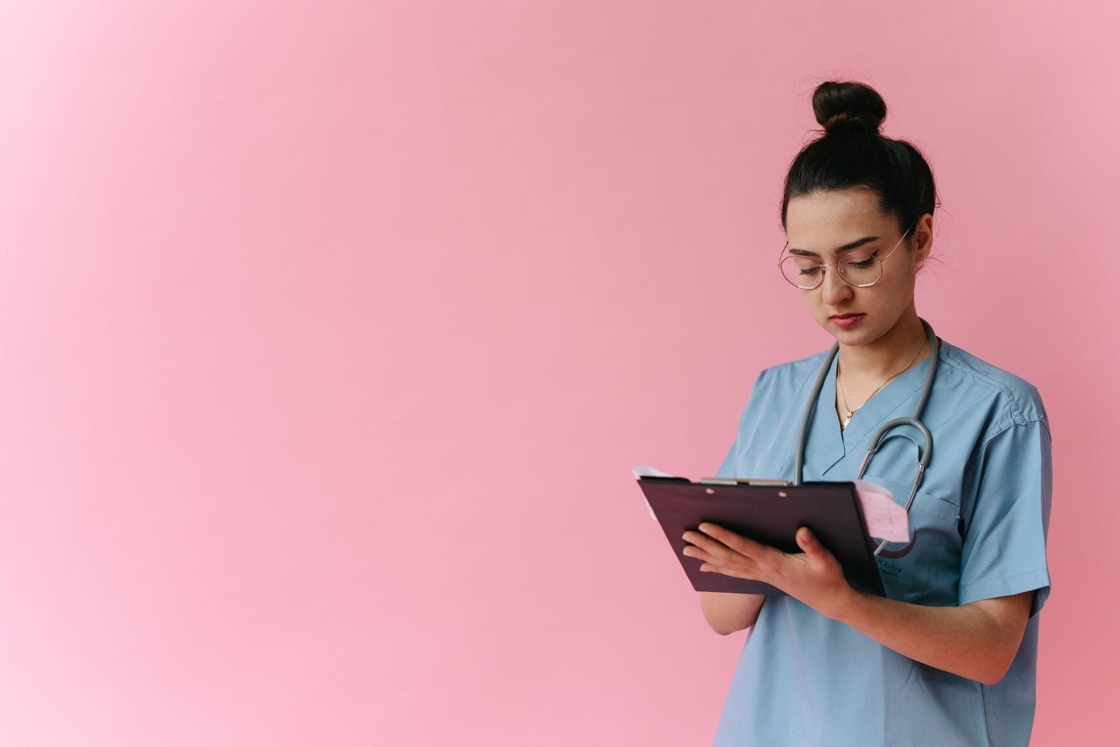 A nurse in scrubs reviewing documentation on a clipboard