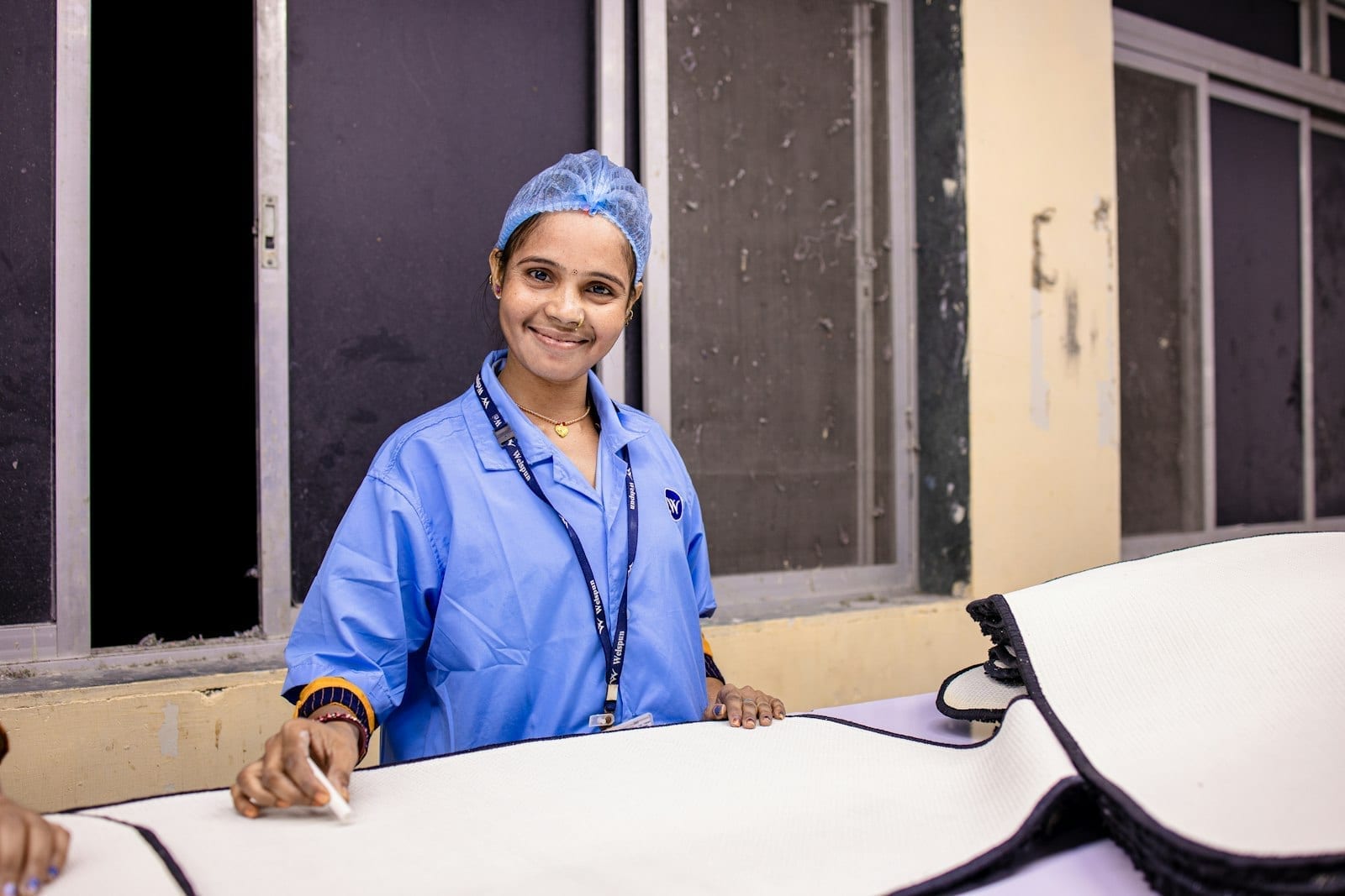 A nurse in surgical attire smiling against a plain background