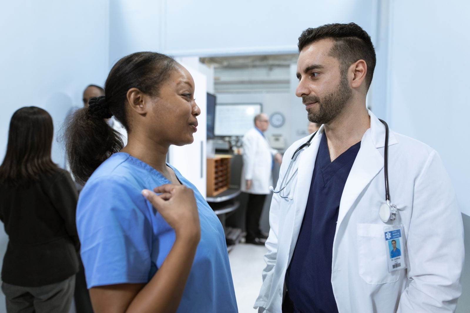 Healthcare workers in scrubs having a discussion in a hospital hallway