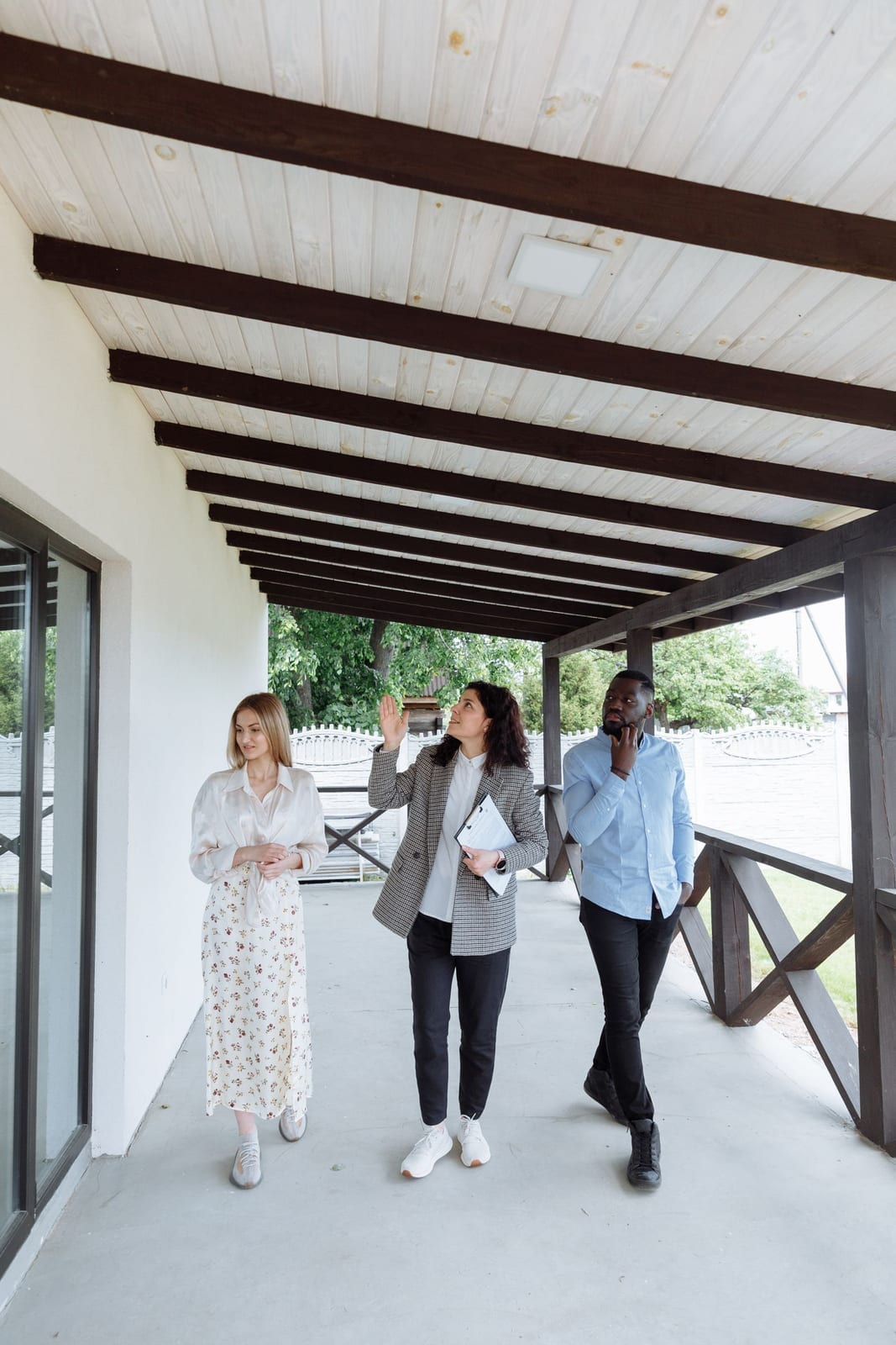 A real estate agent showing a house to clients during a walk-through on a porch
