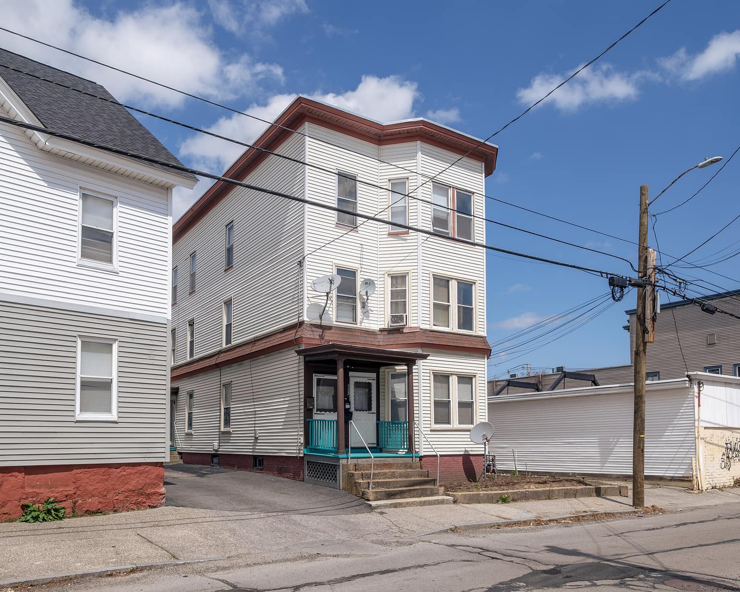 A three-story wooden triple-decker apartment house on Douglas Street in Manchester, New Hampshire